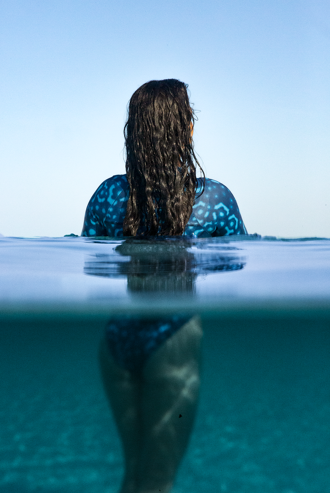 Close-up of eco-friendly Whale Shark swimwear, women’s long-sleeve one-piece in blue and white dotted marine animal print, sustainable active surf swimsuit UK.