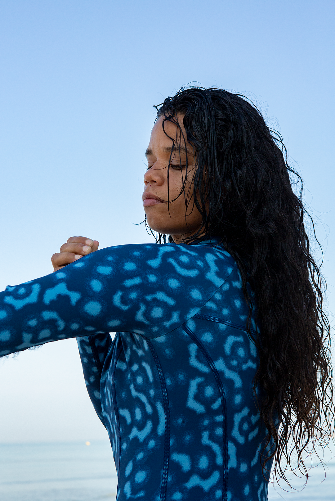 Model wearing eco-friendly Whale Shark print women’s long-sleeve one-piece swimsuit in blue and white dotted marine animal print, sustainable active swimwear UK.