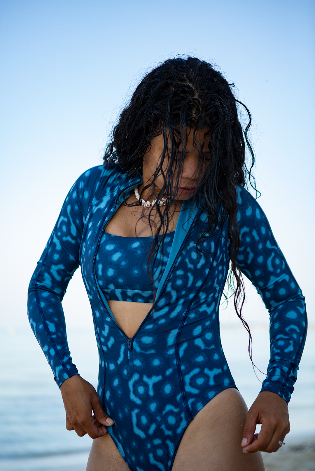 Model wearing eco-friendly Whale Shark print women’s long-sleeve one-piece swimsuit in blue and white dotted marine animal print, sustainable active swimwear UK.