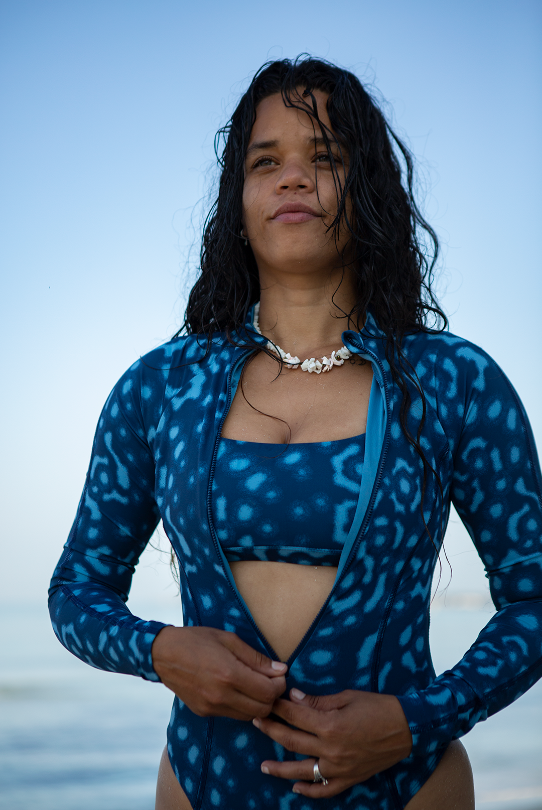 Model wearing eco-friendly Whale Shark print women’s long-sleeve one-piece swimsuit in blue and white dotted marine animal print, sustainable active swimwear UK.
