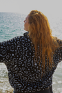 Eagle ray print black and white womens fleece worn on the beach by a red haired woman.