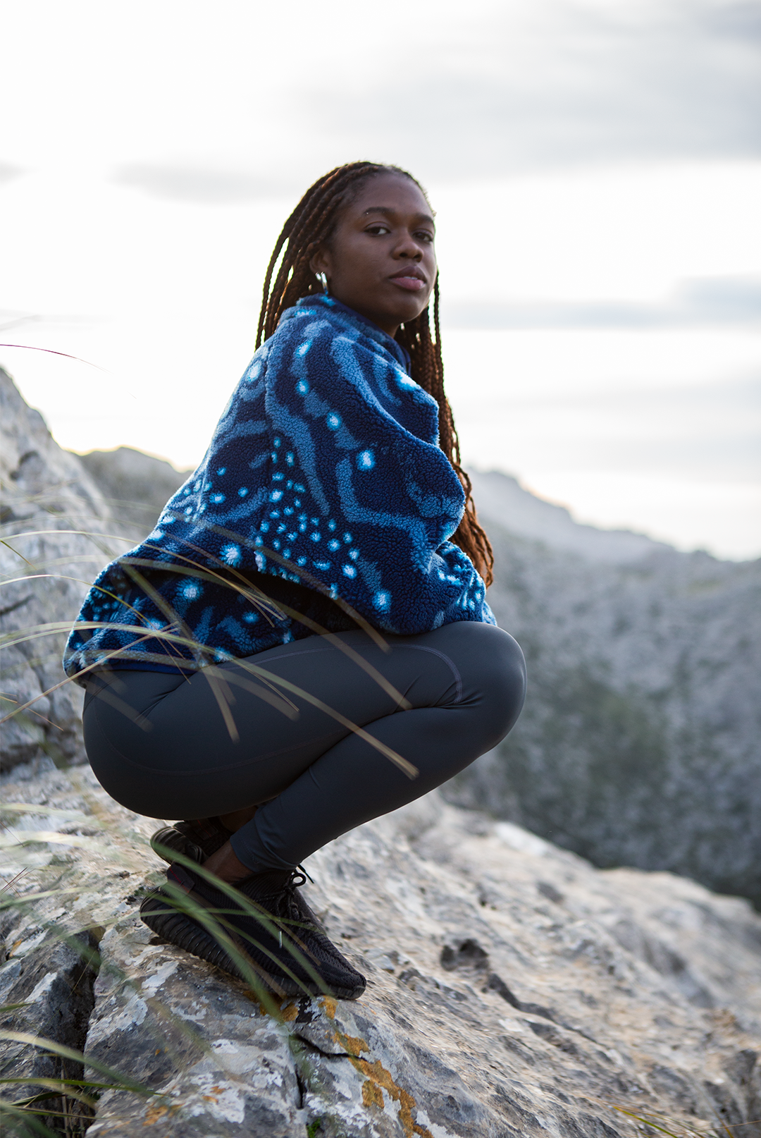 Girl wearing the whale shark print womens fleece from NAUTRA standing on a mountain side. 