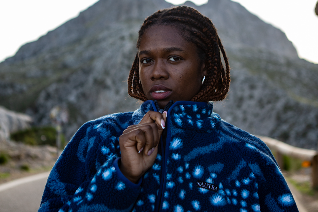 Girl wearing the whale shark print womens fleece from NAUTRA standing on a mountain side. 