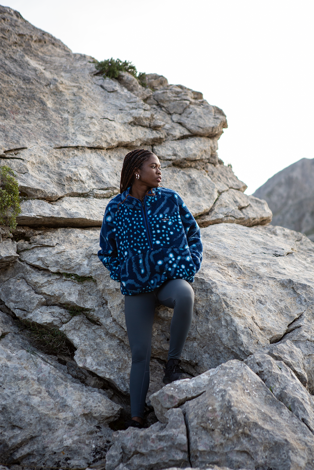 Girl wearing the whale shark print womens fleece from NAUTRA standing on a mountain side. 