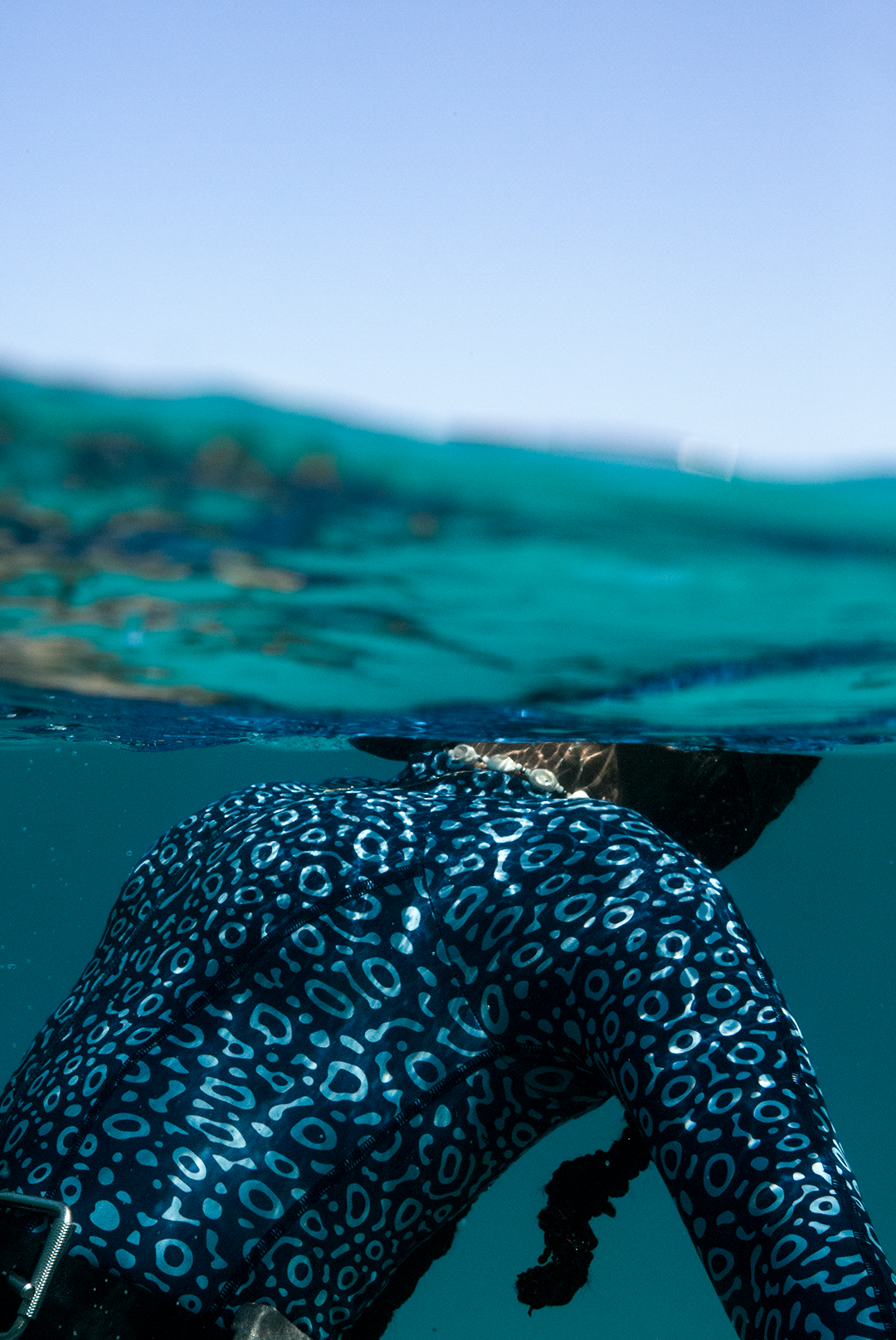 Close-up of eco-friendly Eagle Ray print swimsuit, women&#39;s long-sleeve one-piece design in blue marine animal print, sustainable swimwear UK, active surf swimwear.
