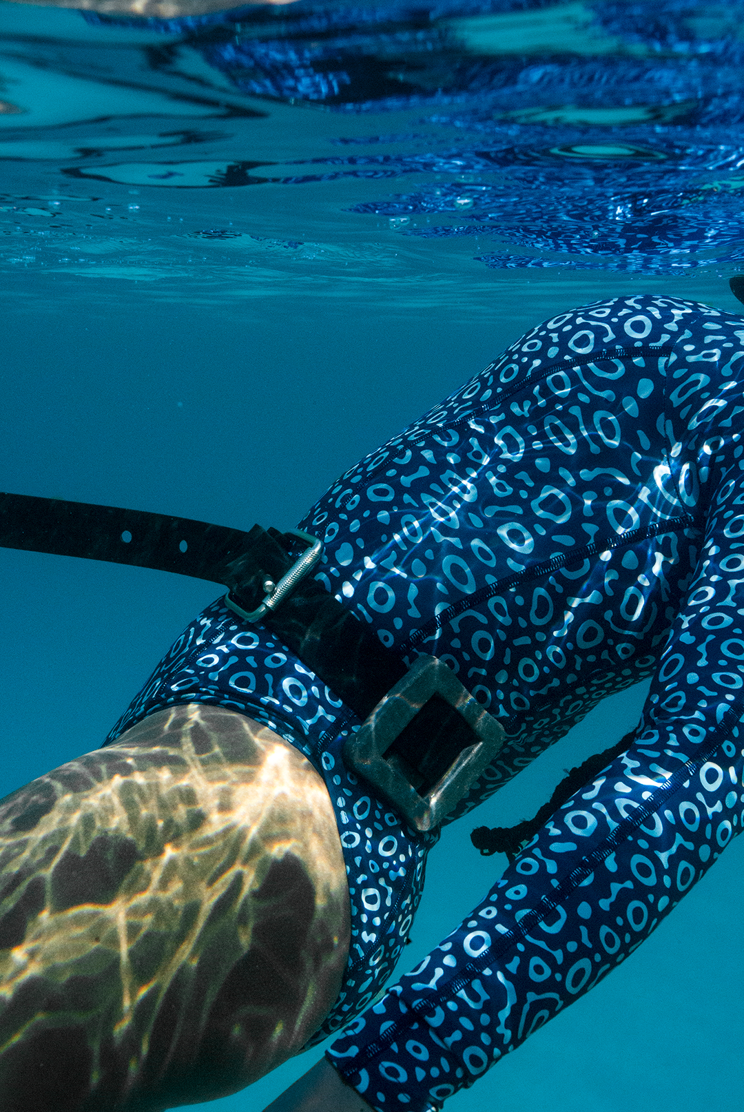 Close-up of eco-friendly Eagle Ray print swimsuit, women&#39;s long-sleeve one-piece design in blue marine animal print, sustainable swimwear UK, active surf swimwear.
