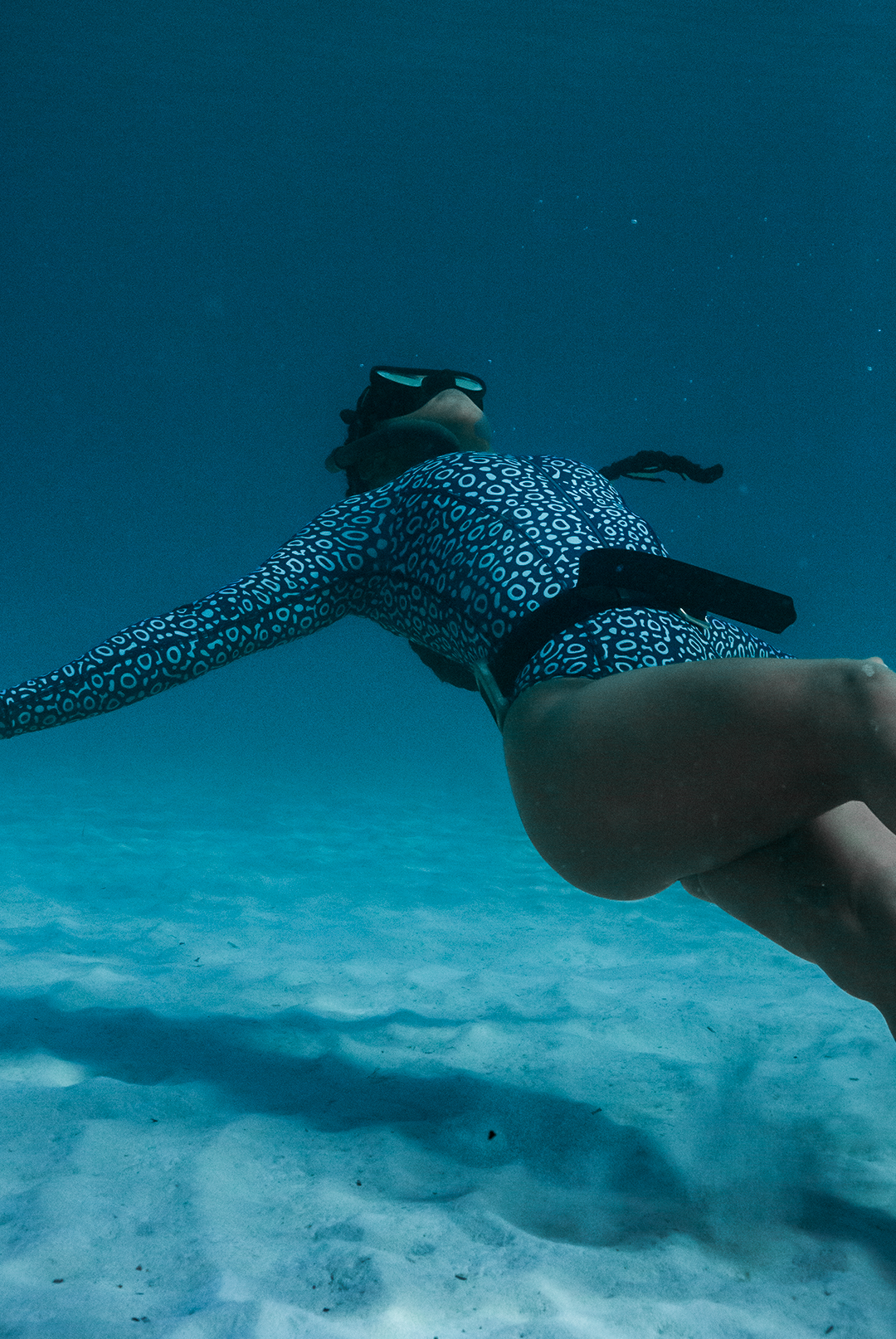 Close-up of eco-friendly Eagle Ray print swimsuit, women&#39;s long-sleeve one-piece design in blue marine animal print, sustainable swimwear UK, active surf swimwear.
