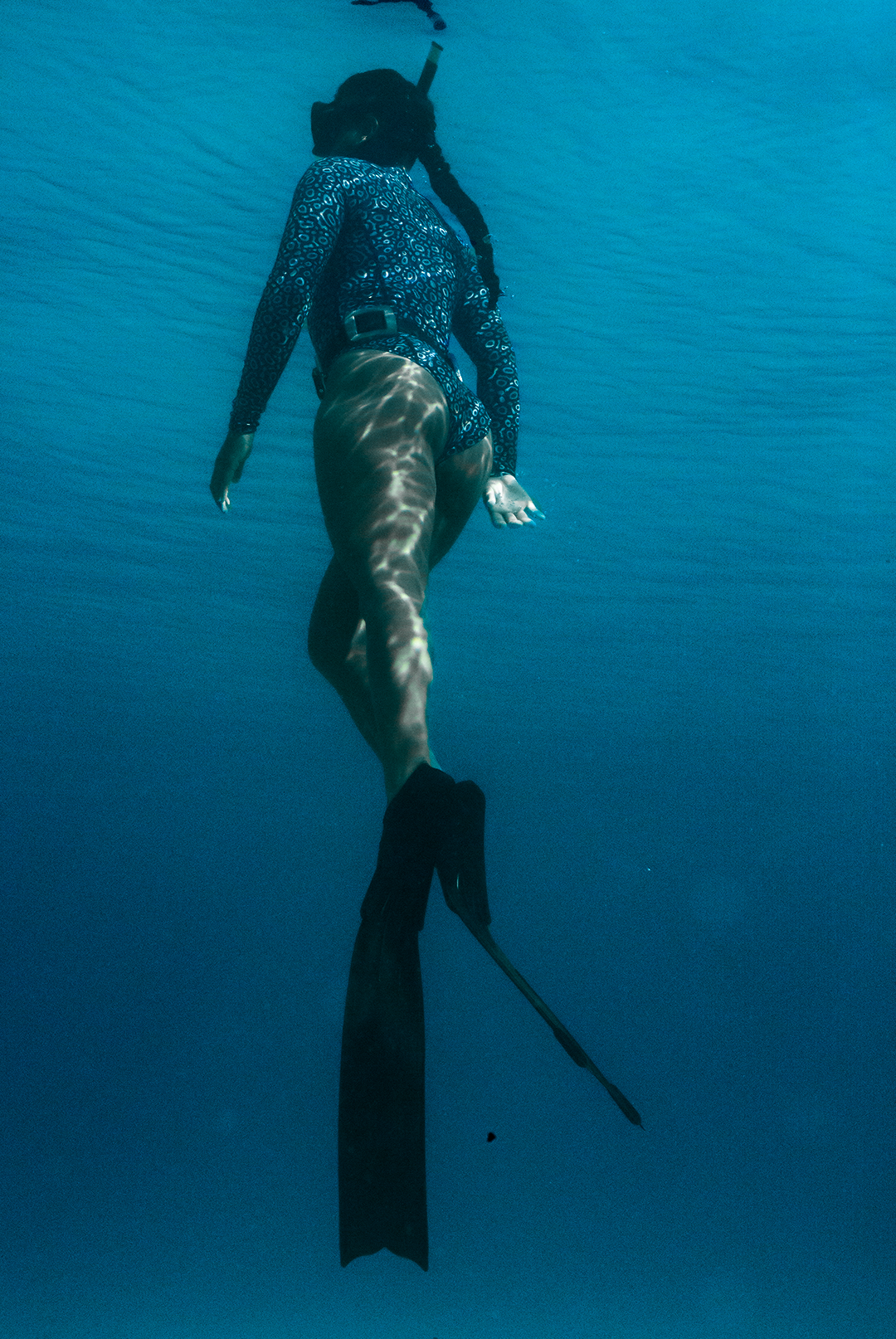 Close-up of eco-friendly Eagle Ray print swimsuit, women&#39;s long-sleeve one-piece design in blue marine animal print, sustainable swimwear UK, active surf swimwear.
