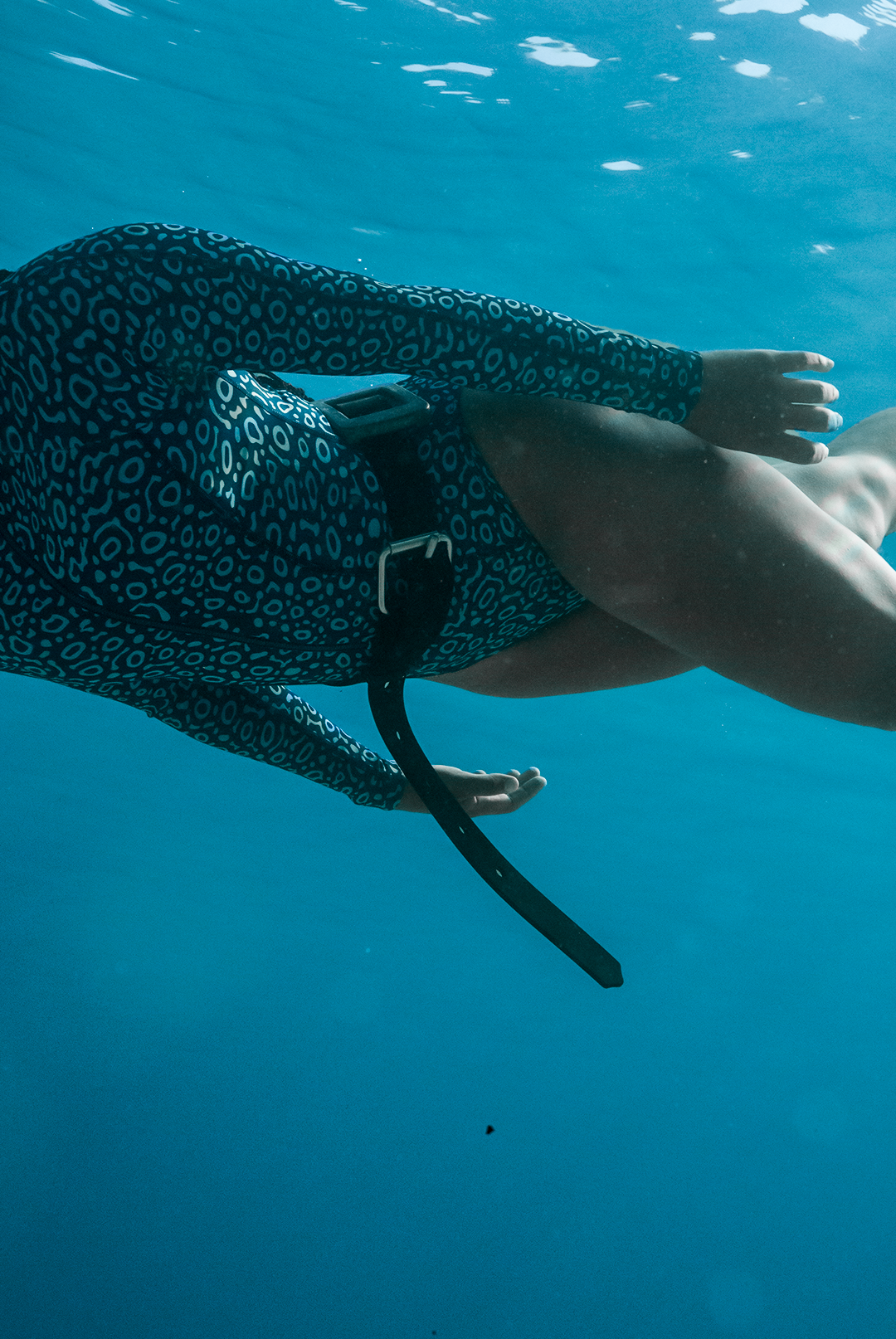 Close-up of eco-friendly Eagle Ray print swimsuit, women&#39;s long-sleeve one-piece design in blue marine animal print, sustainable swimwear UK, active surf swimwear.
