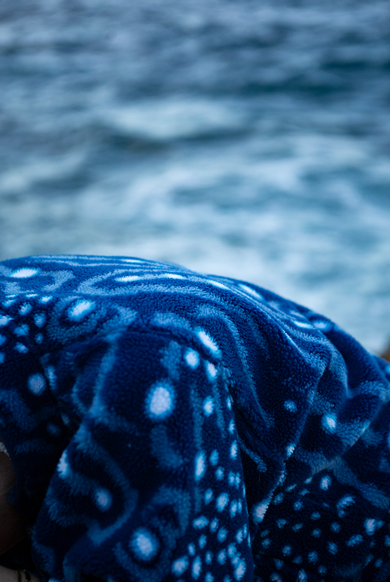 Close-up of the soft recycled fleece fabric showing whale shark spot pattern and sherpa texture.