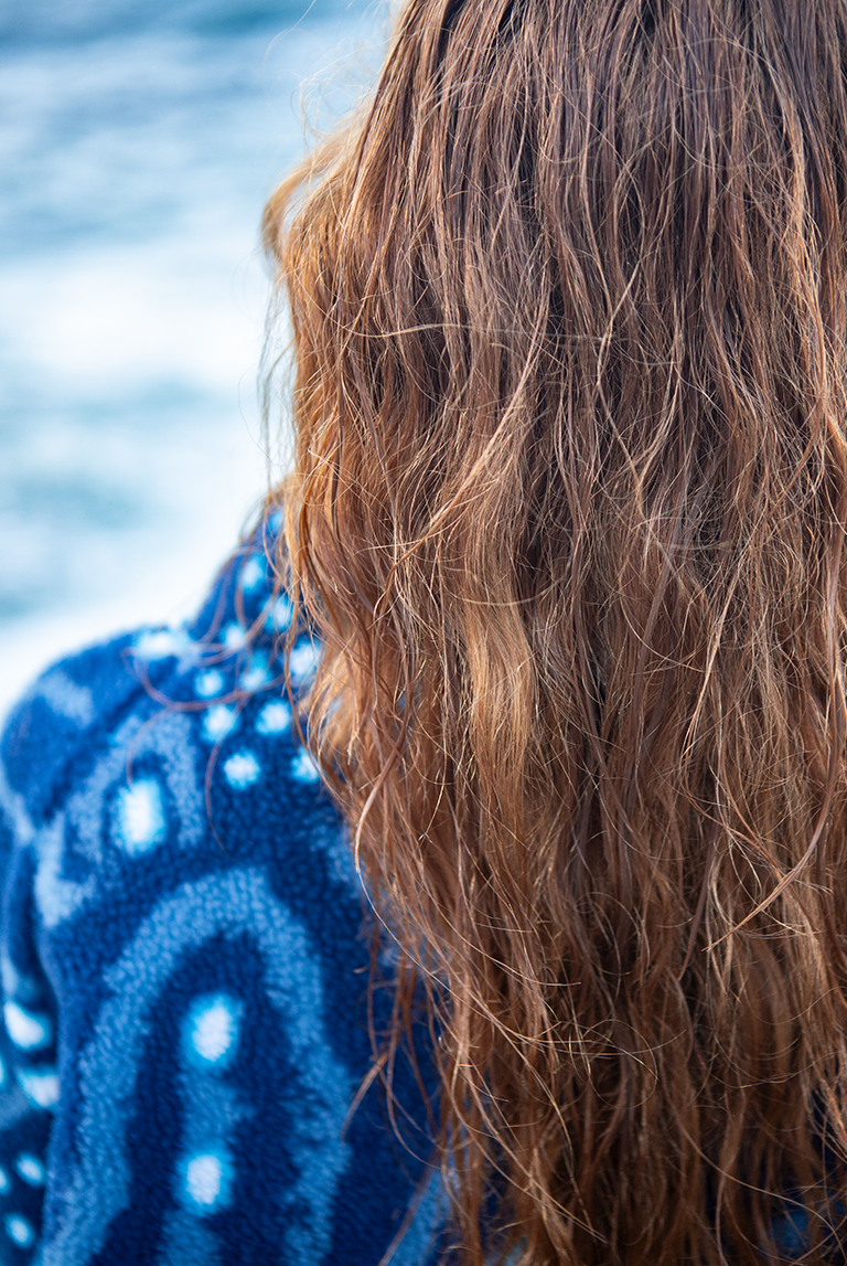 Close-up of model’s wet hair against the whale shark patterned fleece fabric with the ocean softly blurred behind.