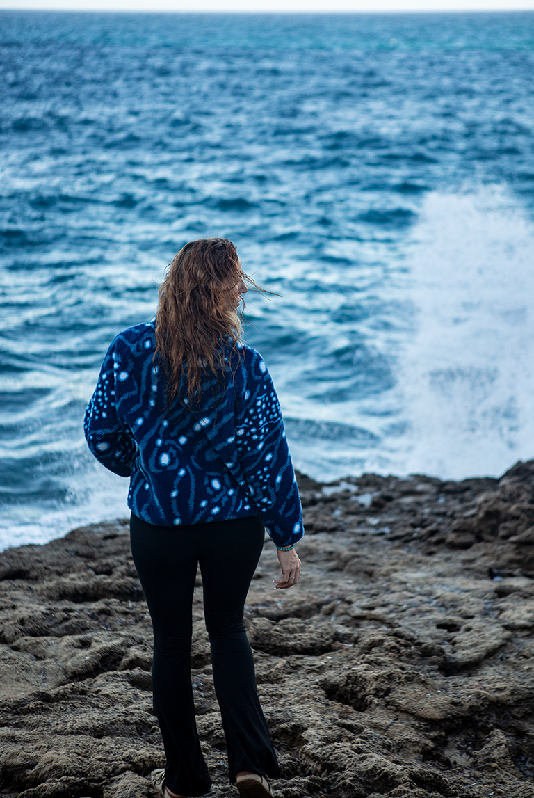 Back view of the NAUTRA Whale Shark Fleece showing the whale shark-inspired blue and white pattern, photographed by the sea.