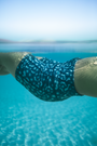 Model wearing eco-friendly Whale Shark print women’s high waist biker shorts in blue and white dotted marine animal print, sustainable active swimwear UK with side pockets.
