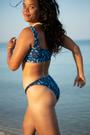Model wearing eco-friendly Whale Shark print women’s bikini bottoms in blue and white dotted marine animal print, high leg style swimwear made from ghost nets, sustainable UK.
