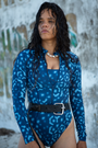 Model wearing eco-friendly Whale Shark print women’s long-sleeve one-piece swimsuit in blue and white dotted marine animal print, sustainable active swimwear UK.
