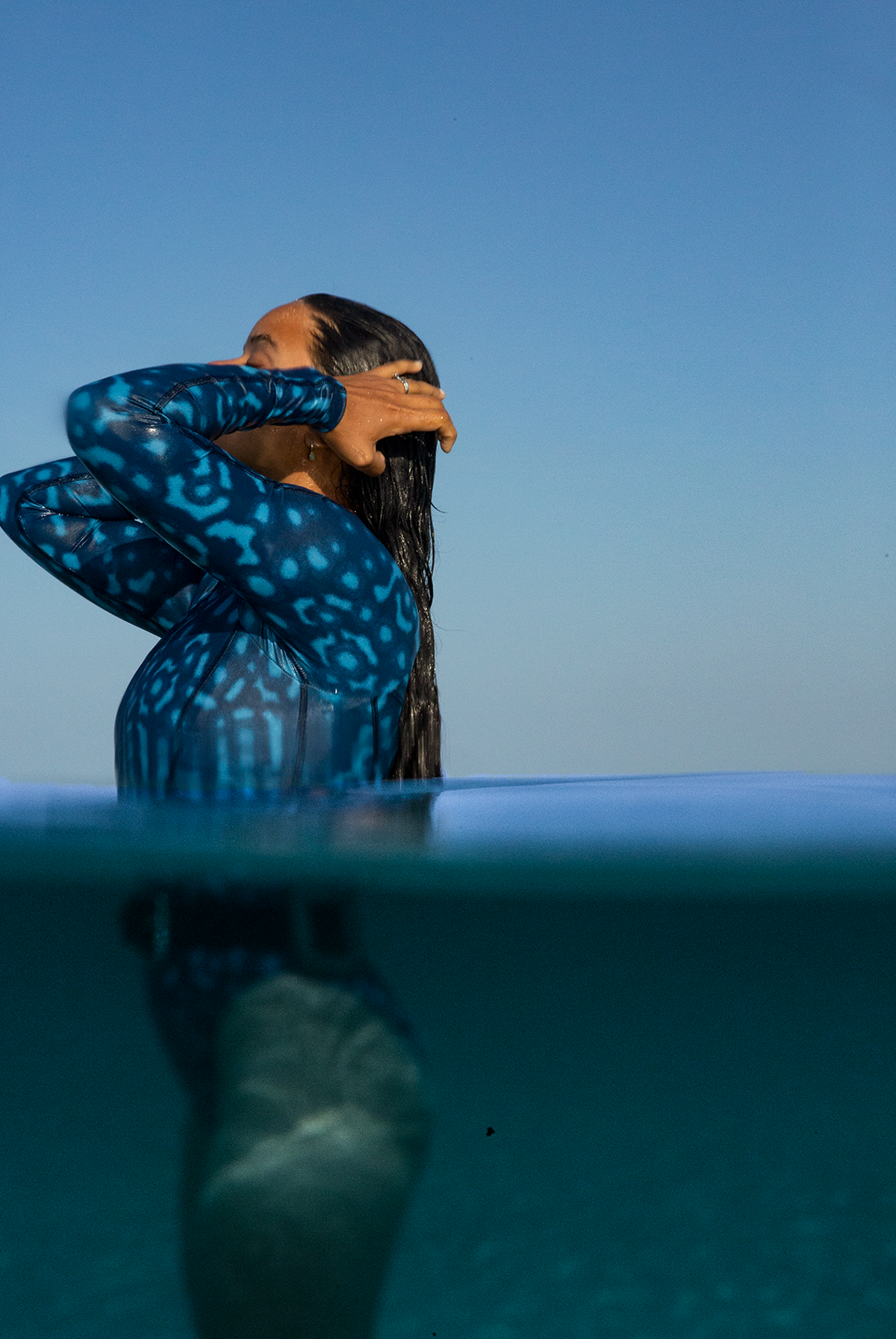 Close-up of eco-friendly Whale Shark swimwear, women’s long-sleeve one-piece in blue and white dotted marine animal print, sustainable active surf swimsuit UK.
