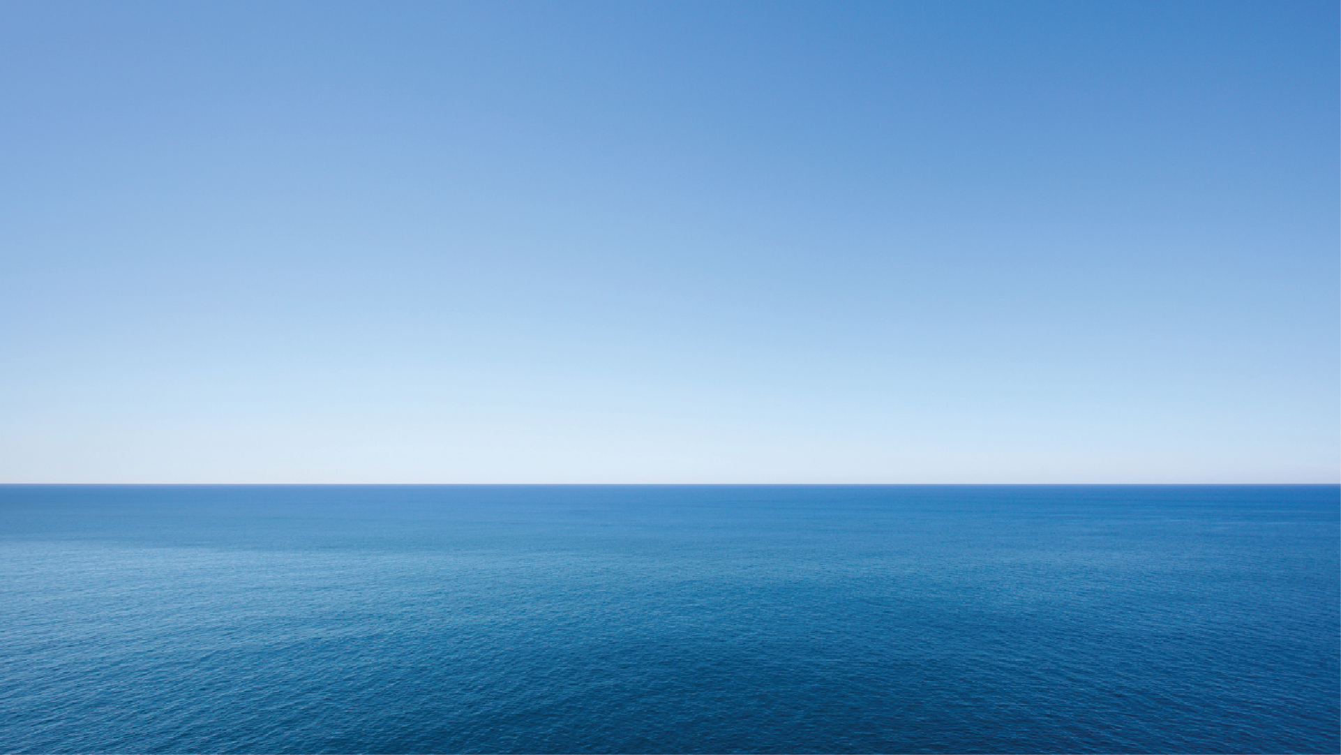 Wide expanse of blue ocean meeting a clear blue sky