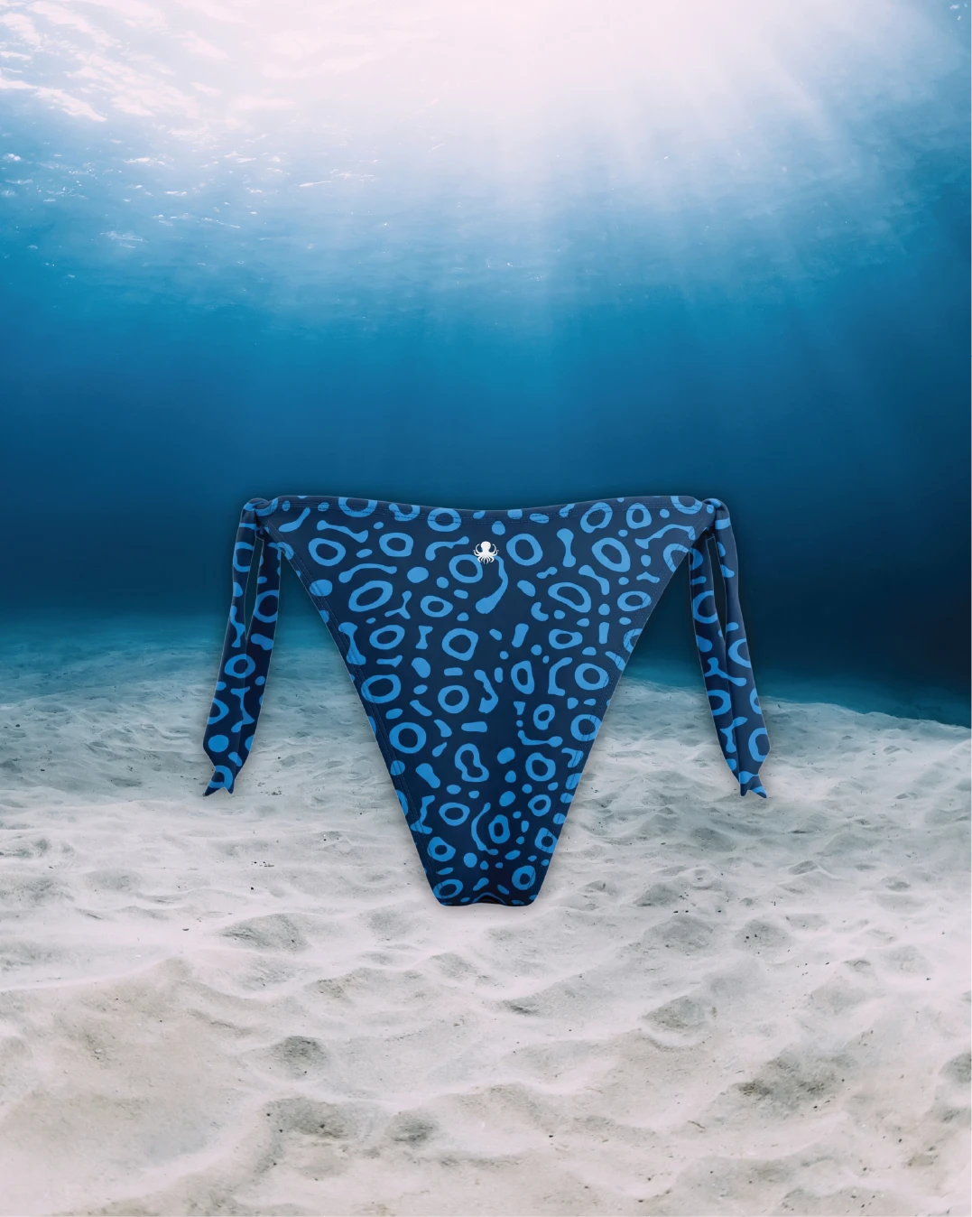 Eagle Ray Tie Side Bikini Bottoms back view on ghost mannequin, made from recycled fishing nets and designed for movement in and around the water.