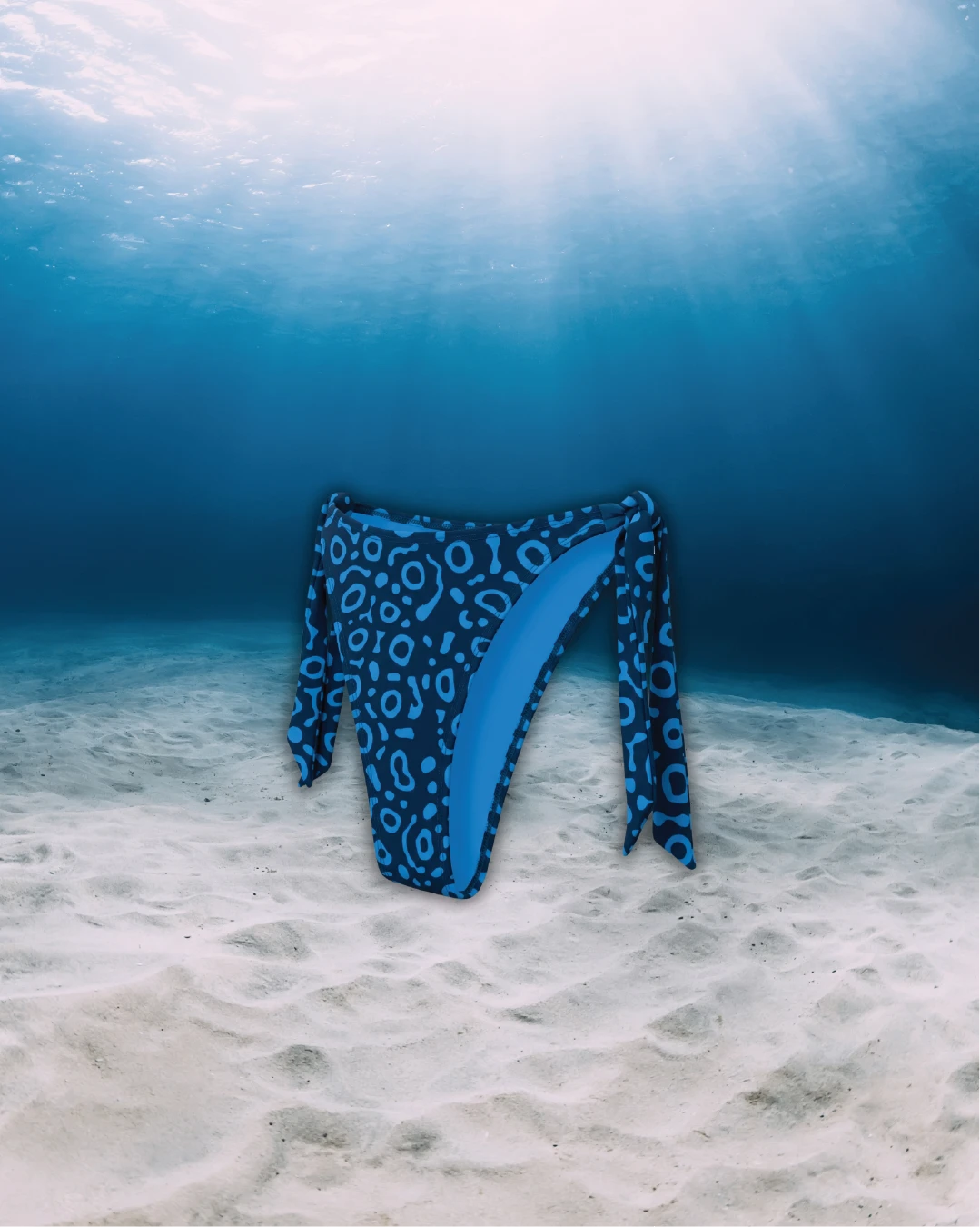 Eagle Ray Tie Side Bikini Bottoms side view on ghost mannequin, made from recycled fishing nets and designed for movement in and around the water.