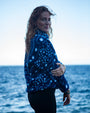 Woman wearing NAUTRA Whale Shark recycled sherpa half zip fleece standing by the ocean.